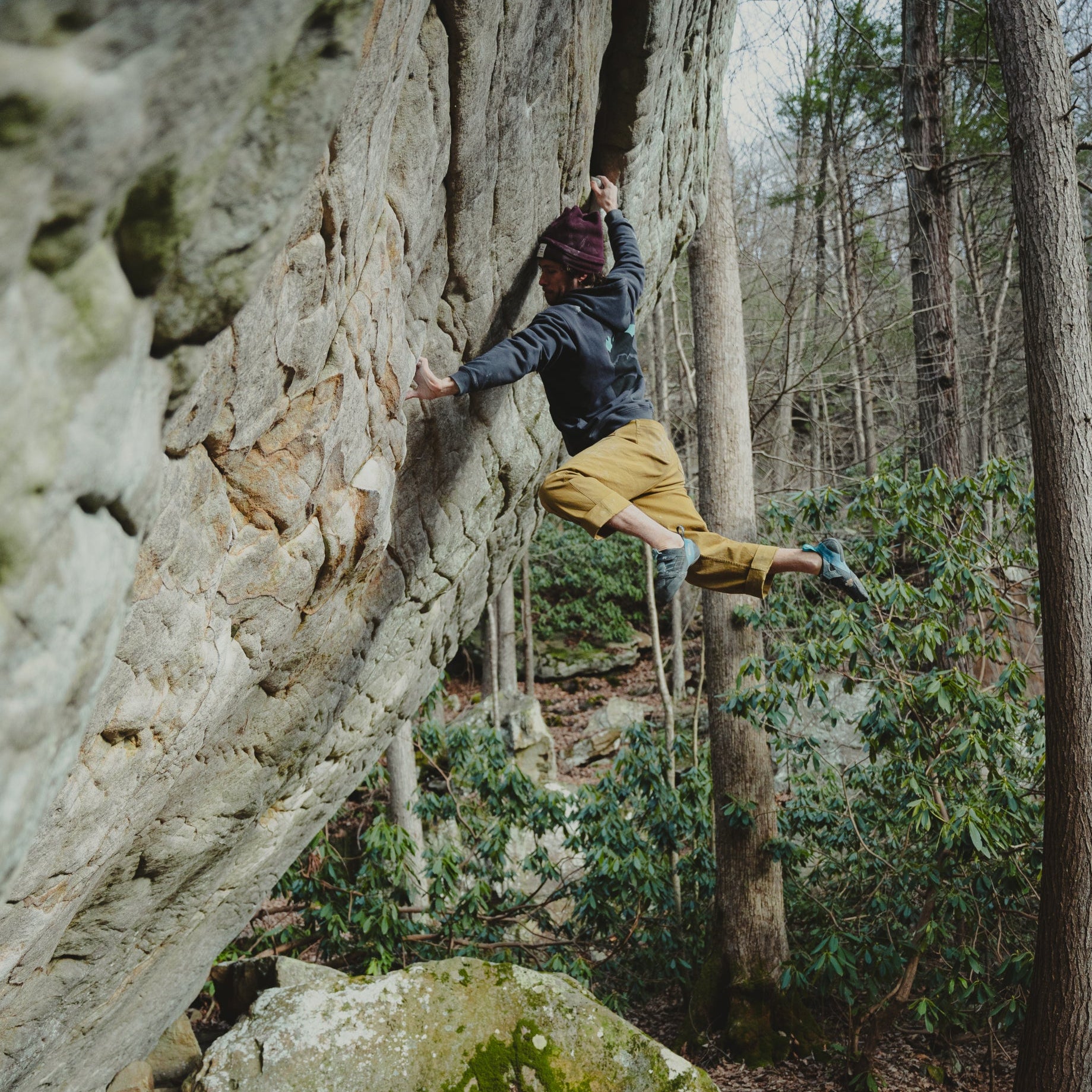 A bouldering throws for a move deep in the forest. 